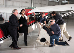Dennis Parmer and Stacy Bynes plan the music with Martin Nicholas, while  David Smith and Jay Robinson inspect a shipment of “refreshments” for the Speakeasy Party at the Anson Aviation Hangar.