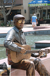 This bronze sculpture in Sugar Land Town Square’s public plaza depicts a guitar player sitting on the ledge of a fountain.